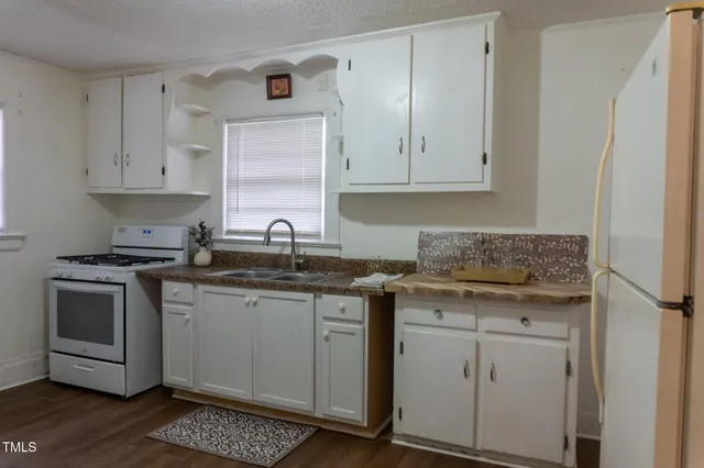 a kitchen with granite countertop white cabinets and white appliances