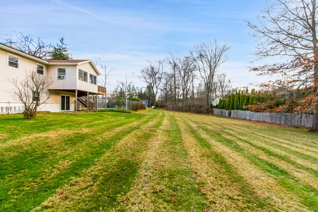 a view of a white house with a big yard and large trees