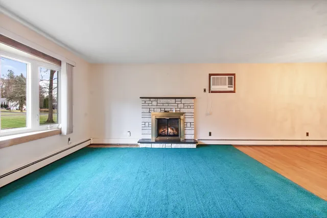 a view of an empty room with window and a fireplace