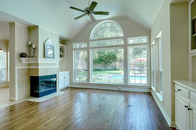 a view of an empty room with a window and wooden floor