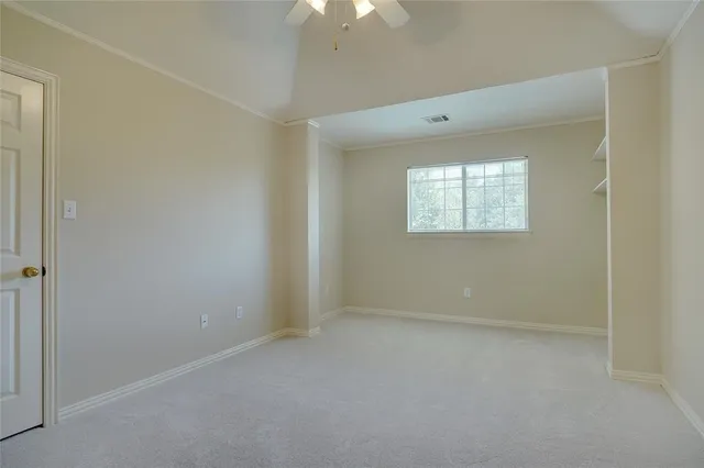 an empty room with windows and chandelier fan