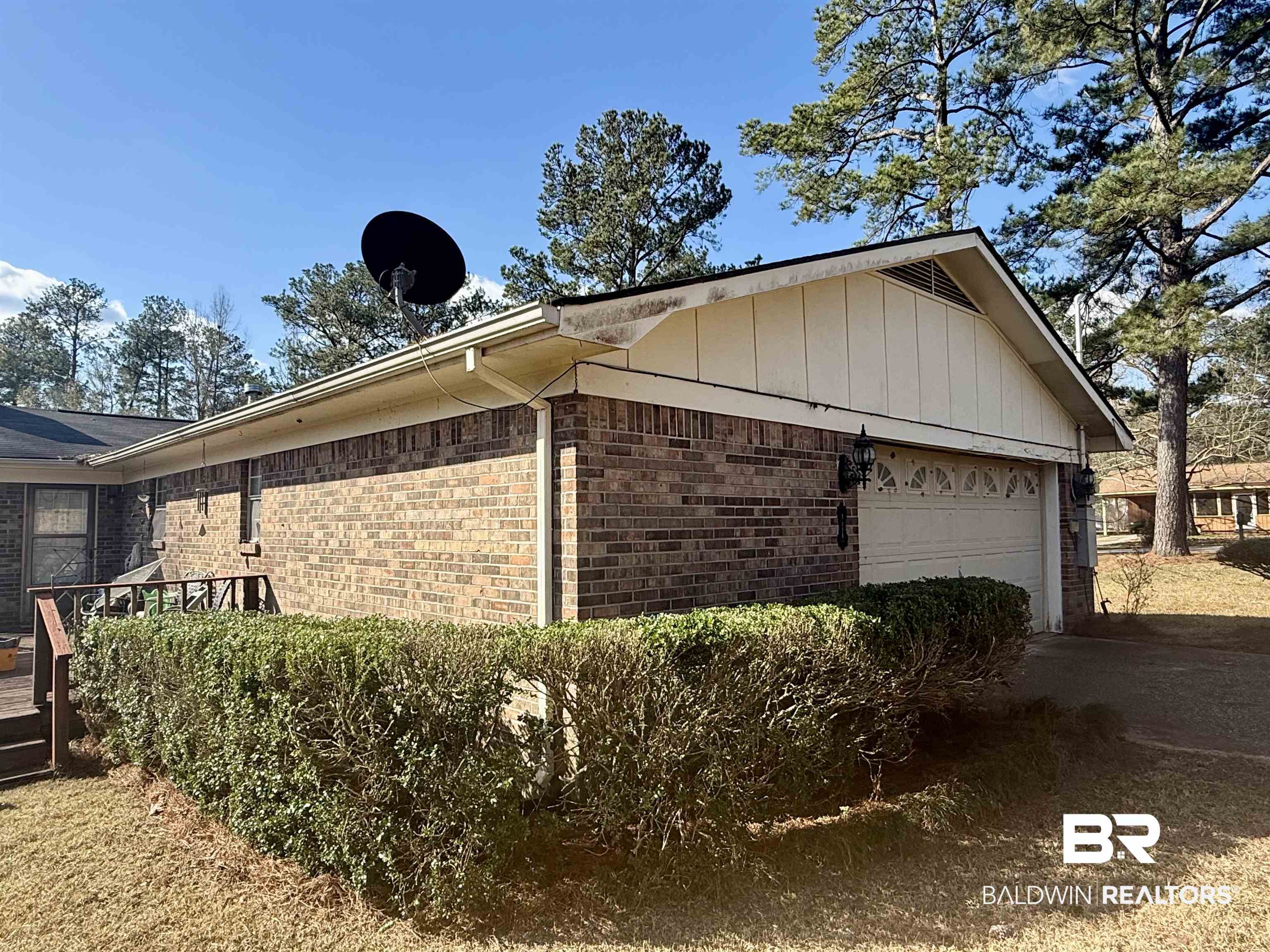 215 Young Street Brewton, AL 36426 - Photo 19 of 25 View of home's exterior featuring brick siding, an attached garage, board and batten siding, a wooden deck, and driveway
