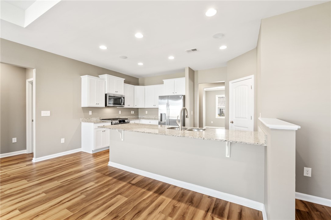 127 Spyglass Lane Pendleton, SC 29670 - Photo 24 of 45 Polished hardwood flooring runs through a modern kitchen featuring granite counters and recessed lighting.