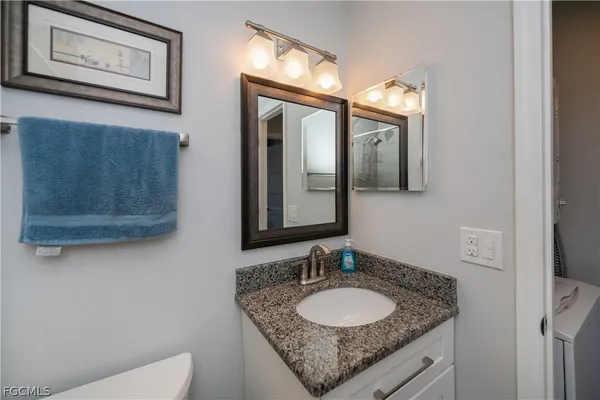 a bathroom with a granite countertop sink a mirror and a toilet