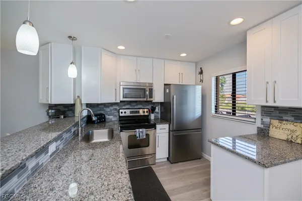 a kitchen with granite countertop a refrigerator a stove a sink and a counter top space