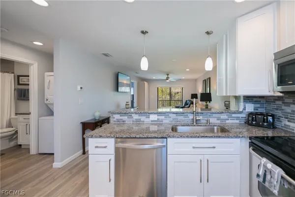 a kitchen with kitchen island granite countertop a sink cabinets and stainless steel appliances
