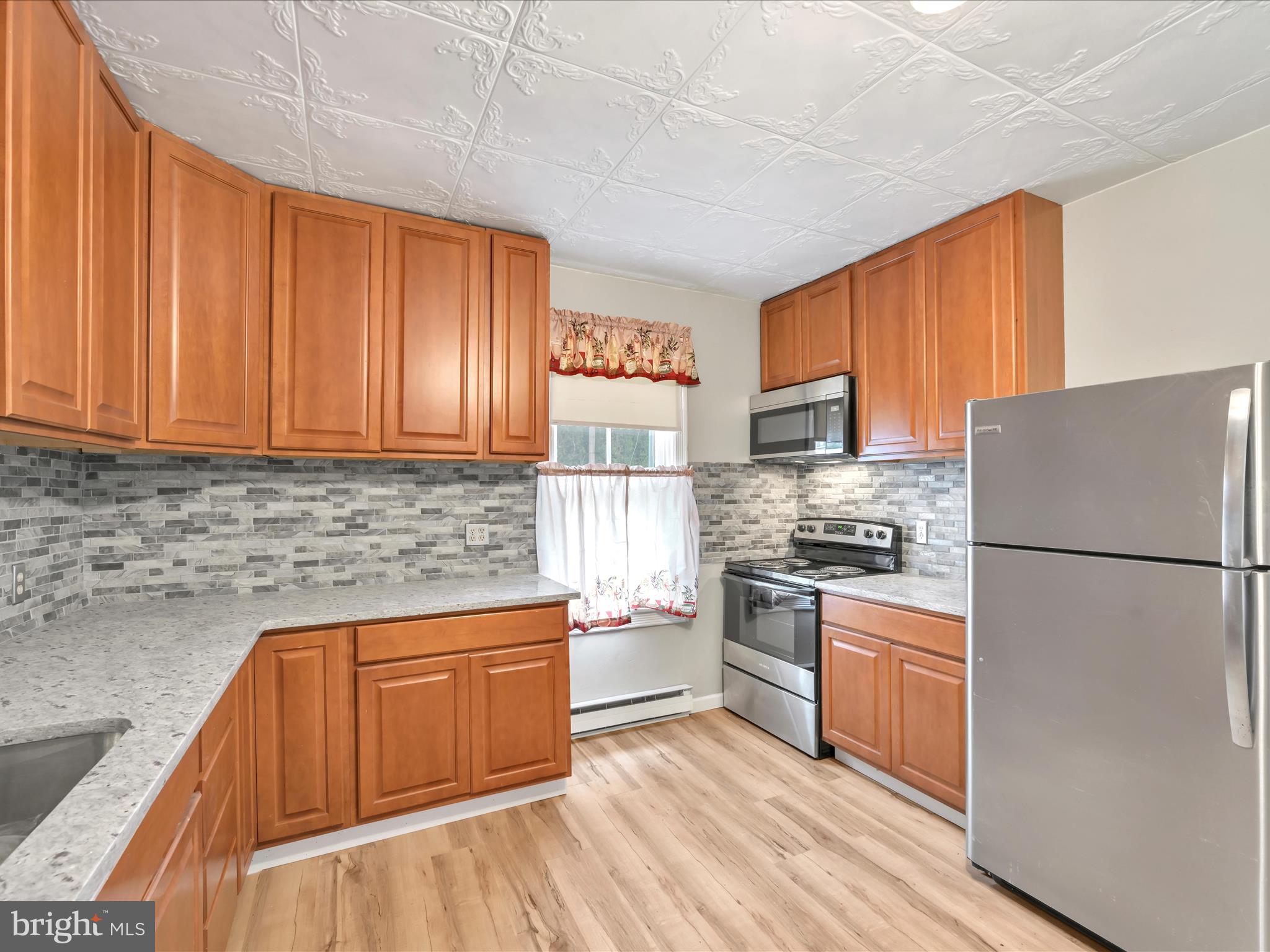 235 Biddle Street Gordon, PA 17921 - Photo 7 of 33 a kitchen with a refrigerator a stove top oven a sink and dishwasher with wooden floor