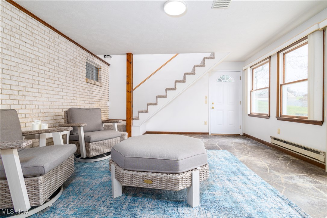 137 Preston Road Steubenville, OH 43953 - Photo 28 of 38 Living area with stairway, stone finish floor, brick wall, visible vents, and a baseboard radiator
