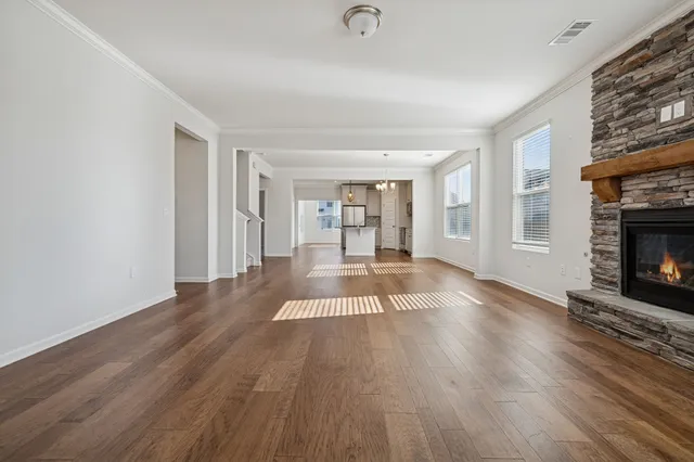 a view of an empty room with wooden floor fireplace and a window