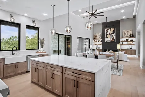 a large kitchen with kitchen island a large counter space a sink appliances and a large window