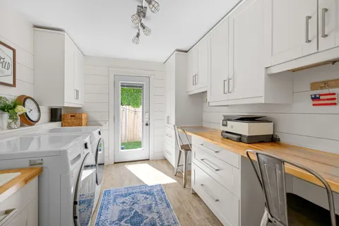 a kitchen with stainless steel appliances granite countertop a stove a sink dishwasher and white cabinets with wooden floor
