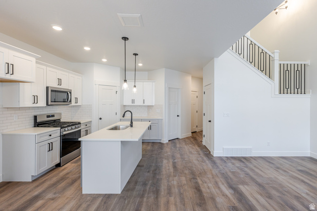 4775 Olive Avenue, Unit 412 Mapleton, UT 84664 - Photo 8 of 19 Kitchen featuring stainless steel appliances, white cabinetry, a center island with sink, pendant lighting, and dark wood-style floors