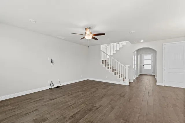 an empty room with wooden floor and a ceiling fan