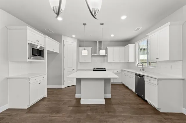 a kitchen with white cabinets appliances and a sink