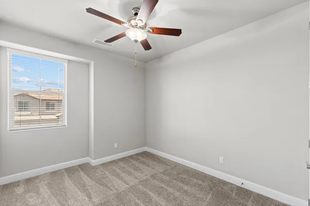 an empty room with a window and a fan