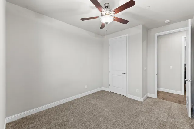 an empty room with a fan & a ceiling fan