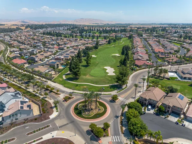 an aerial view of a residential houses with outdoor space and trees