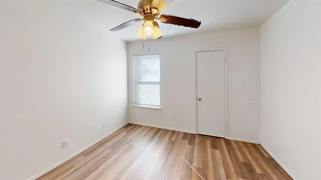a view of an empty room and chandelier fan