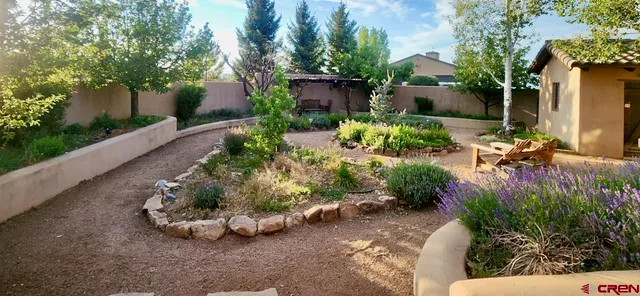 a view of a patio with table and chairs under an umbrella with a barbeque grill and plants