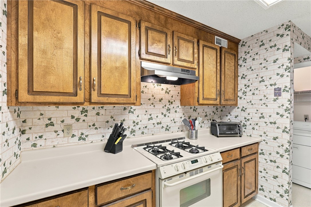 7 Woodbridge Circle Anderson, SC 29621 - Photo 12 of 26 Classic wooden cabinetry pairs with patterned wallpaper in this functional cooking space.