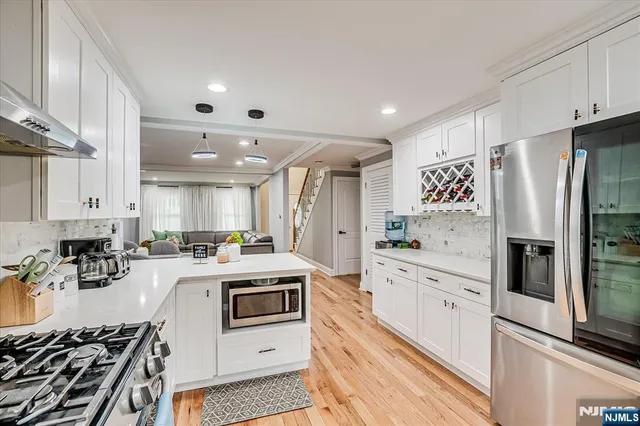 a kitchen with refrigerator a stove a sink dishwasher and white cabinets with wooden floor