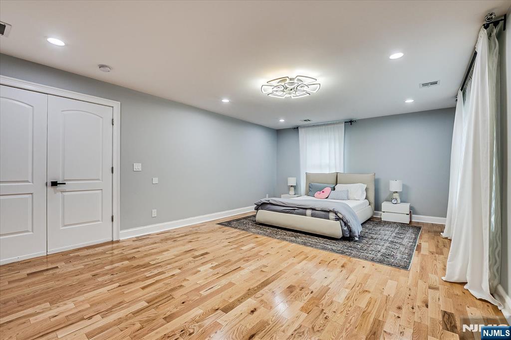 174 Manhattan Avenue Teaneck, NJ 07666 - Photo 18 of 45 a spacious bedroom with a bed and a chandelier