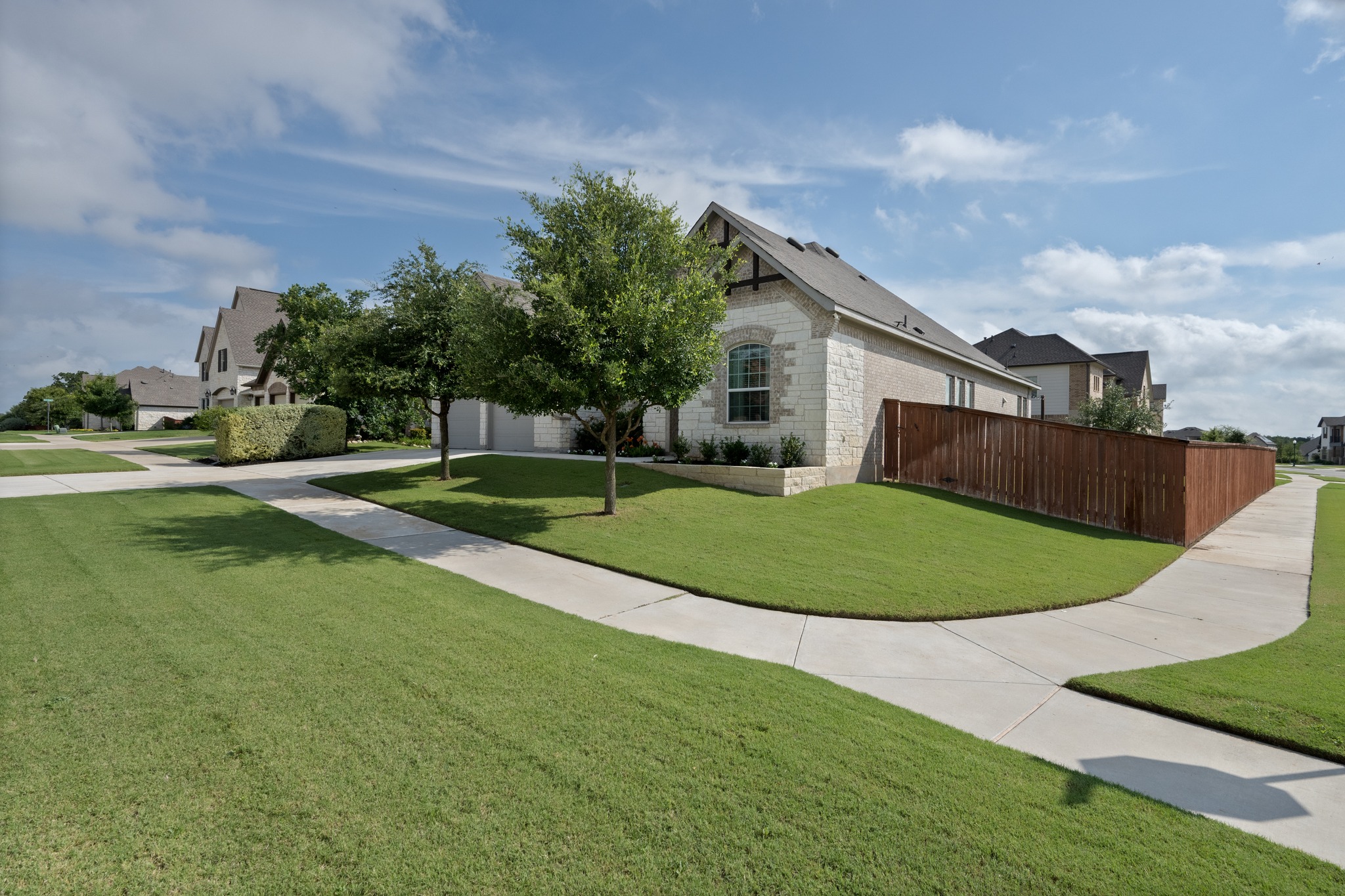 2100 Highland Ridge Road Georgetown, TX 78628 - Photo 2 of 30 Manicured lawns and sidewalks frame this appealing residential street, leading to a charming home with stone detailing.