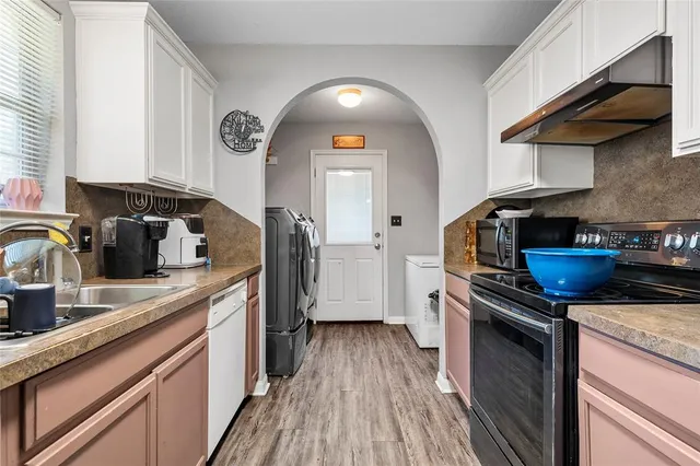 a kitchen with granite countertop a sink a counter space appliances and cabinets