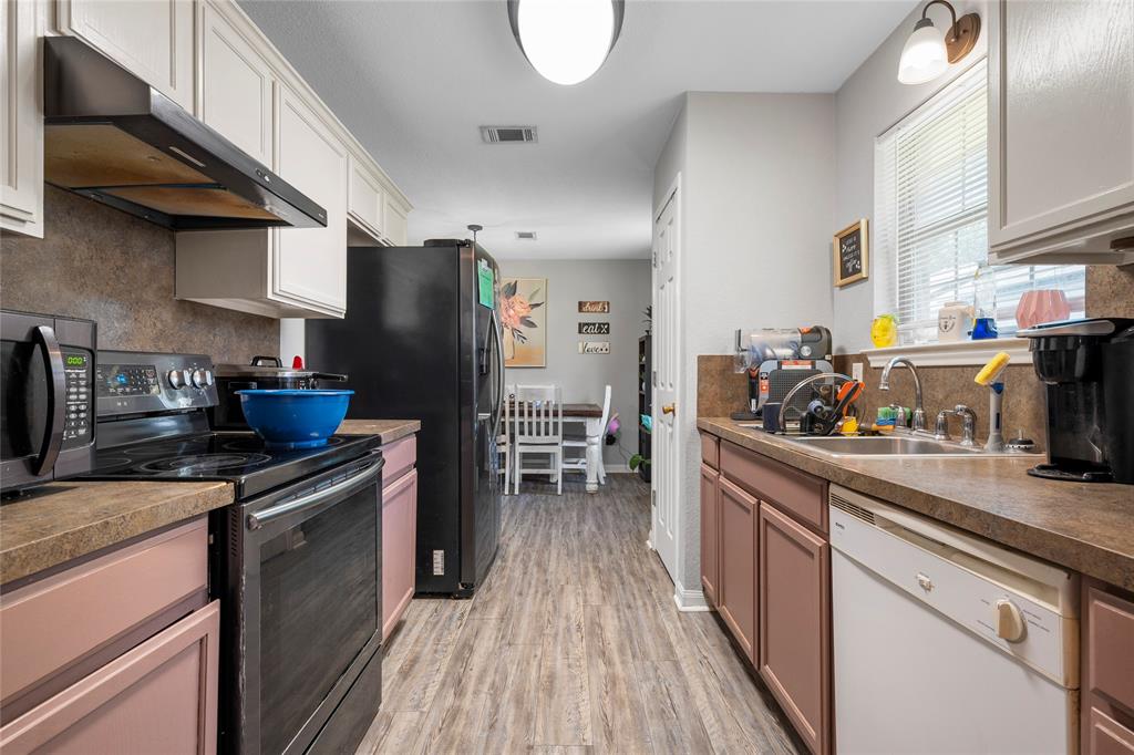 1108 Spring Street Waco, TX 76704 - Photo 7 of 17 a kitchen with stainless steel appliances granite countertop a refrigerator a stove and a wooden floors