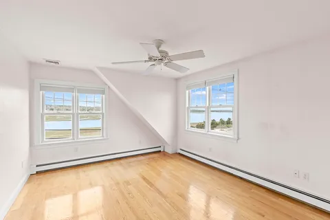 an empty room with windows and ceiling fan
