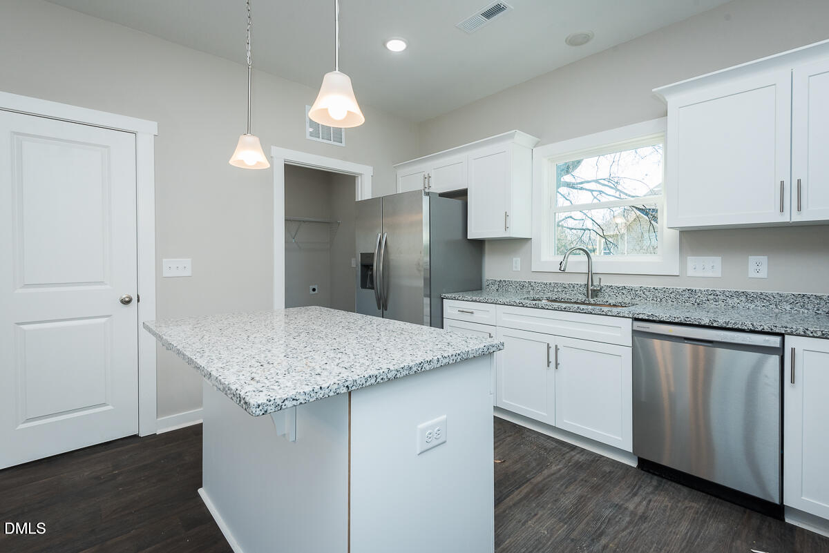 555 Pinnix Road Burlington, NC 27217 - Photo 9 of 20 a kitchen with a sink dishwasher a stove and white cabinets with wooden floor