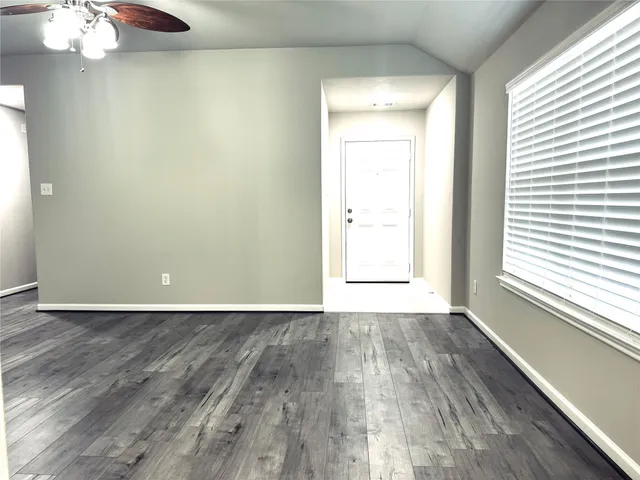 a view of an empty room with wooden floor and a window