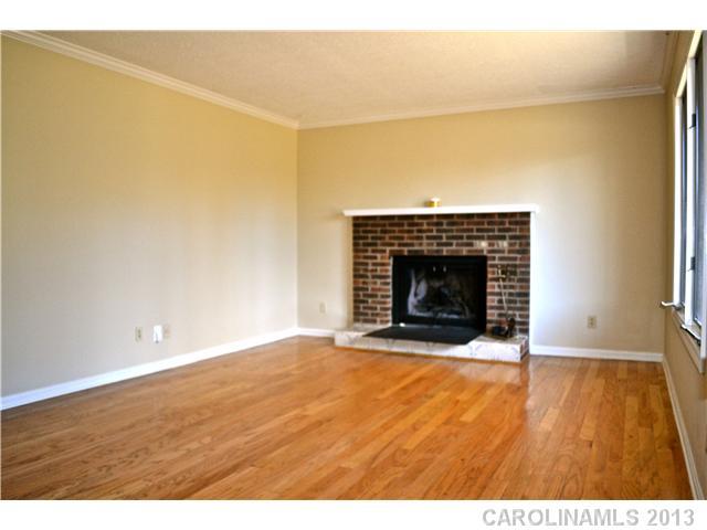 3417 Sandy Porter Road Charlotte, NC 28273 - Photo 6 of 12 a view of an empty room with wooden floor and a fireplace