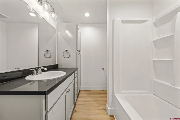 a bathroom with a granite countertop sink a toilet a mirror and shower