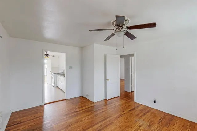 an empty room with wooden floor ceiling fan and windows