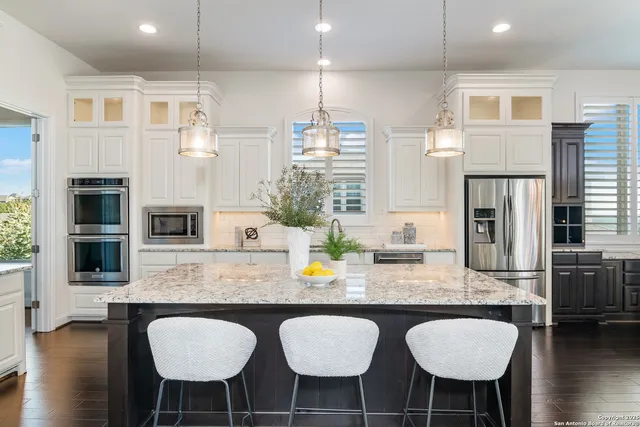 a kitchen with stainless steel appliances granite countertop a kitchen island hardwood floor sink stove dining table and chairs