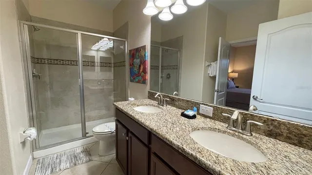a bathroom with a granite countertop sink a toilet and shower