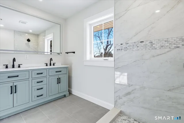 a spacious bathroom with double vanity sink a mirror and shower