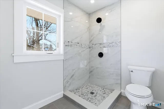 a bathroom with a shower a toilet and a window