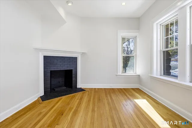 a view of empty room with wooden floor and fireplace