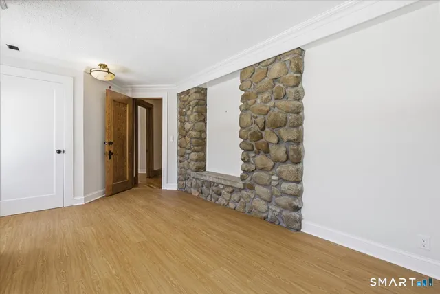 a view of an empty room with window and wooden floor