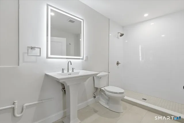 a bathroom with a granite countertop sink a toilet and a mirror