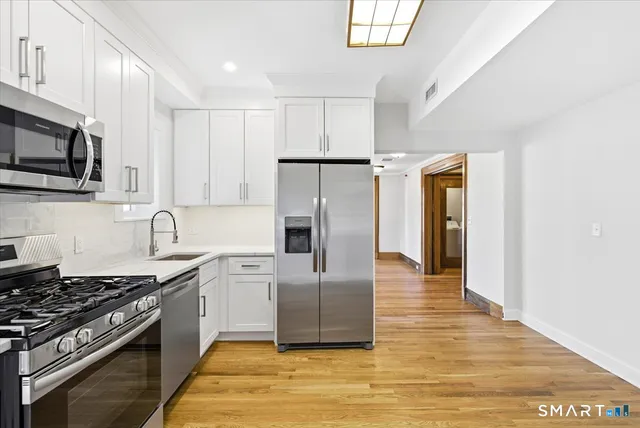 a kitchen with stainless steel appliances granite countertop a stove a refrigerator and a microwave