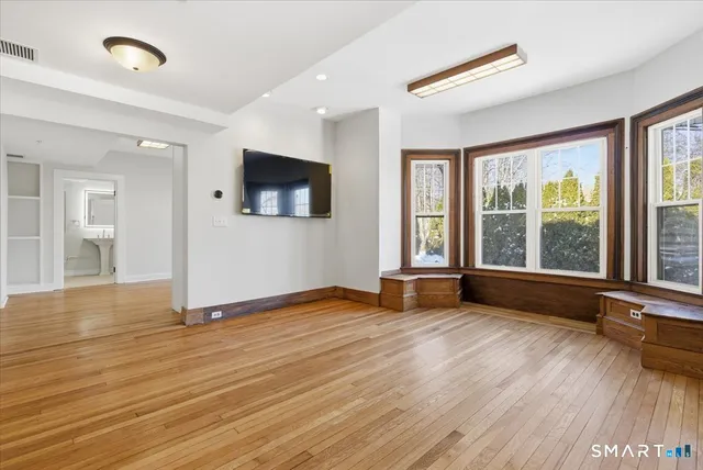 a view of an empty room with wooden floor and a window