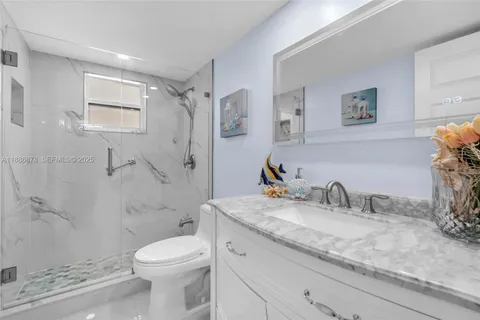 a bathroom with a granite countertop sink a toilet and shower