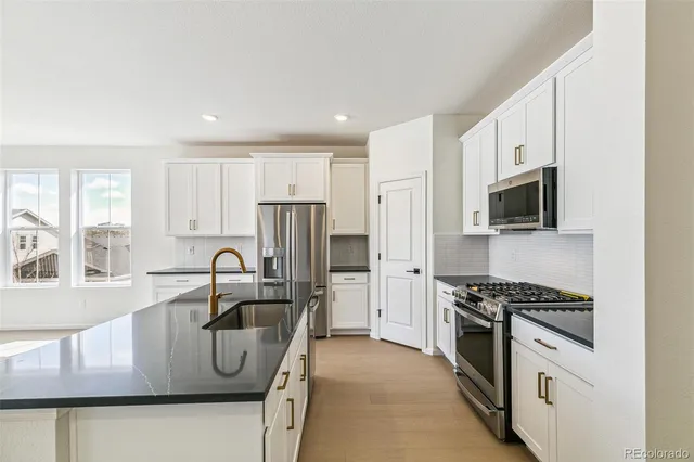 a kitchen with stainless steel appliances granite countertop a stove a sink and a refrigerator with wooden floor