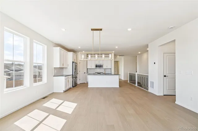 a large white kitchen with kitchen island a large window and white cabinets
