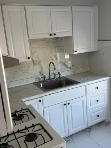 a kitchen with white cabinets a sink and white stove