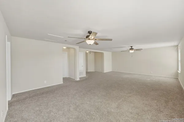 a view of a big room with windows and chandelier fan
