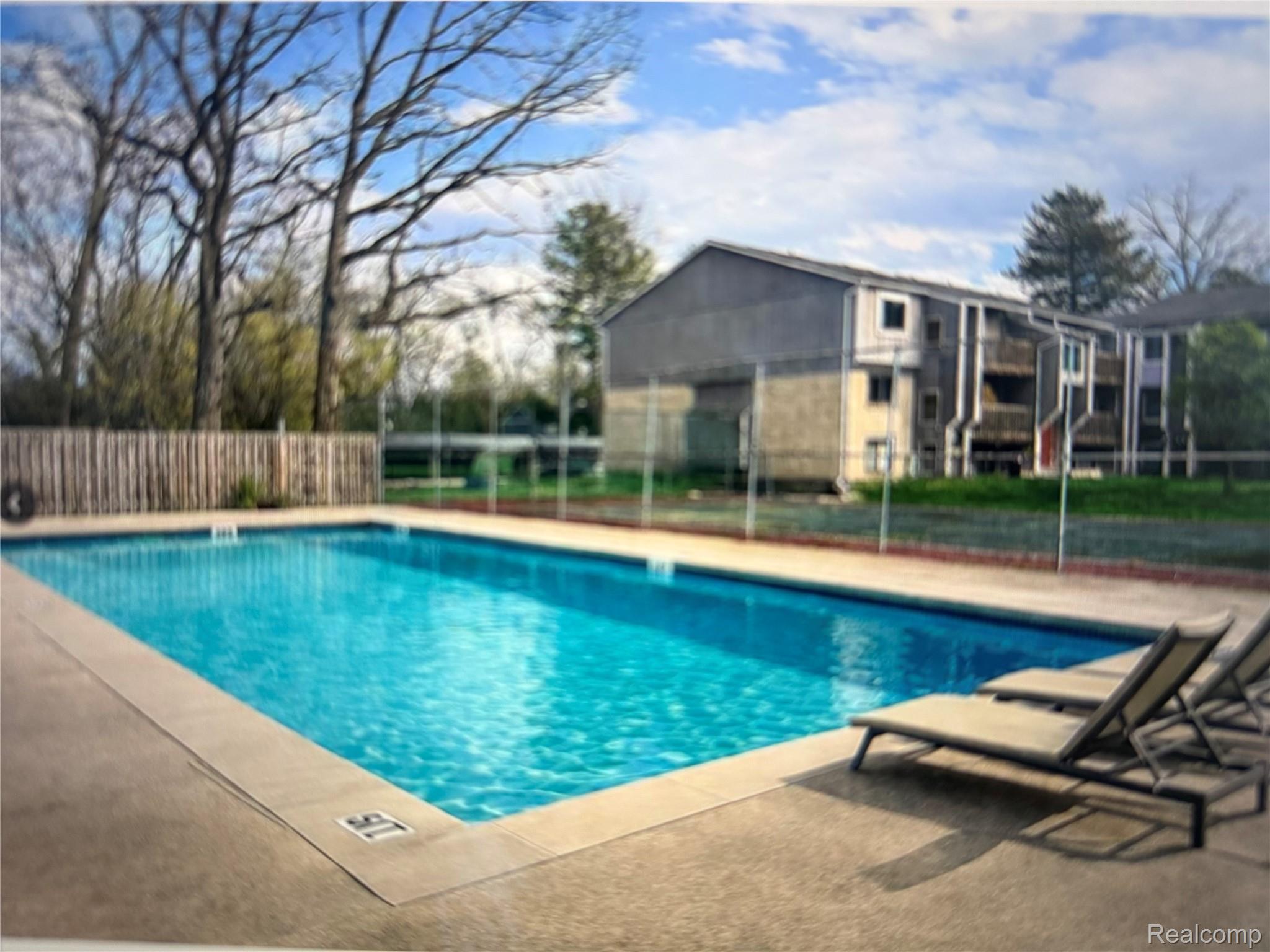 29870 West 12 Mile Road, Unit 703 Farmington, MI 48334 - Photo 37 of 40 Rectangular swimming pool with a concrete surround and a metal fence enclosure